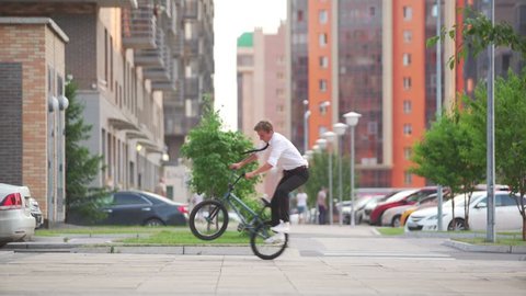 BMX freestyle on the city street. BMX flatland tricks. Hipster on the BMX bike.