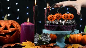 Halloween party table with spooky hand with long black nails stealing a chocolate cupcake.  - Powered by Shutterstock - Get 15% off with code: PIKWIZARD15