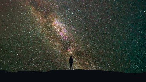 The man stand on a background of a milky way with asteroids skyfall. time lapse
