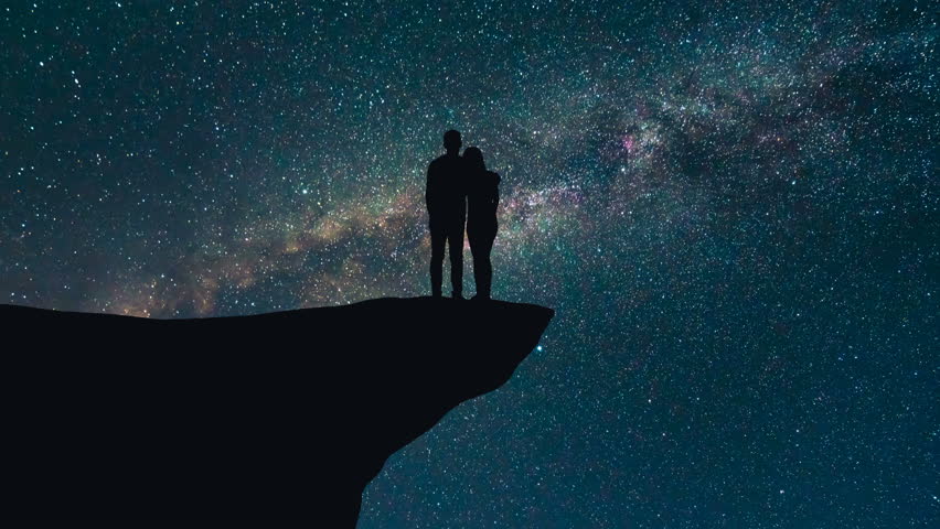 The couple stand on the montain on the starry background. time lapse, night time