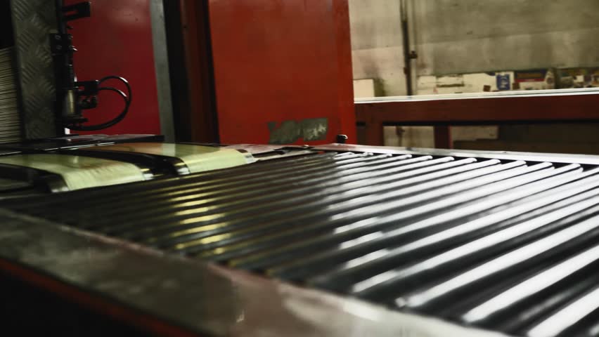 Side view of a man working on newspaper production line in newspaper factory