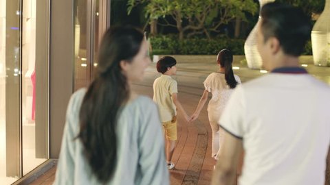 rear view of asian family of 4 walking at a shopping area at night วิดีโอสต็อก