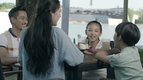 asian family drinking & talking at outdoor seating enjoying happy family time in slow motion స్టాక్ వీడియో