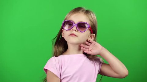 Child posing for video cameras with glasses. Green screen. Slow motion