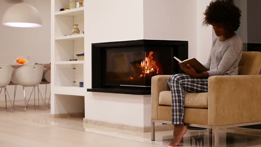 black woman using tablet at moder villa beside fireplace