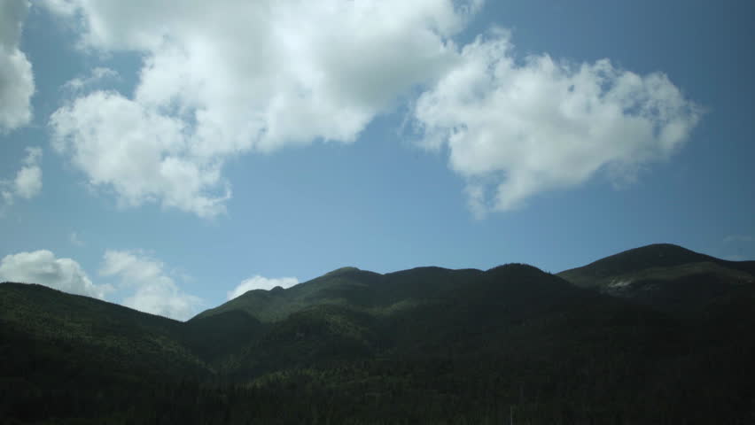 Clouds float through blue skies float over the Adirondack mountains.