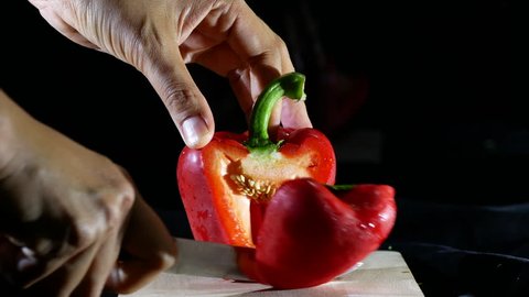 Chef cutting a bellpepper on black background