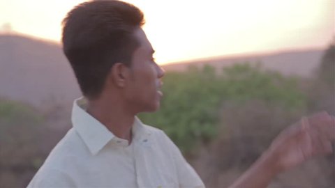 Confident young man from rural India talking with his friend while sun is rising in the background