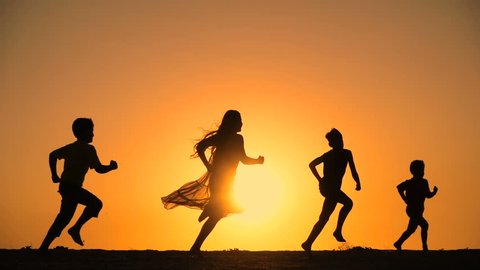 silhouette of five kids running at hill against sunset, slow motion