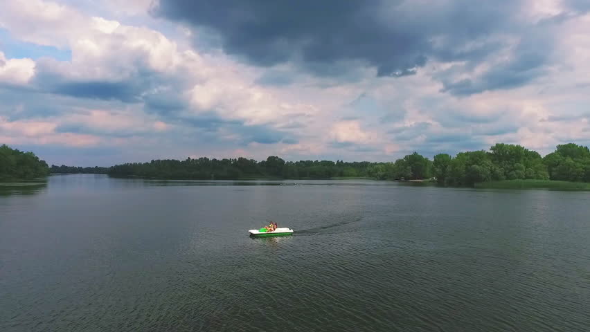 Flying over girls floating pedal boat on lake water HD aerial panoramic video. Women relaxation on river at summer vacation. Recreation leisure nature background