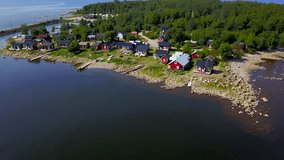A beautiful view of small Scandinavian houses on the Baltic Sea shore on a clear sunny day. 4K aerial video.