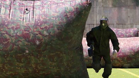 Paintball player running and was shooted HD game slow-motion video. Man with gun running on playing field venue. Sport action war battle fighting