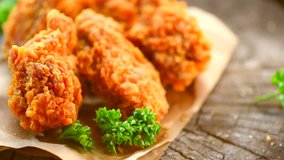 Crispy fried chicken wings and legs on a wooden table rotation 360 degrees. Breaded Crispy fried chicken tasty dinner. 4K UHD video footage. Ultra high definition 3840X2160 