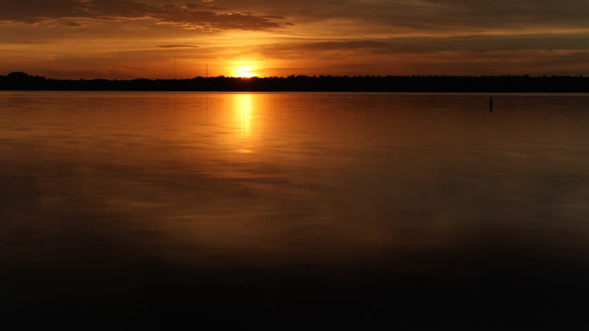 Shimmering golden sunrise over water. HD 1080p time lapse. Zoom in.