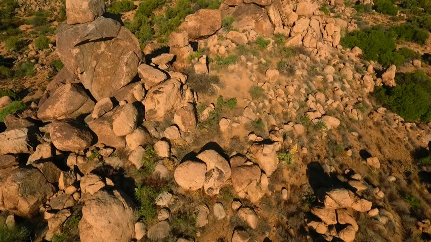 Aerial flyover of desert rock formations and large boulders