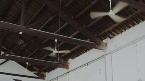 Three symmetrical and identical ceiling fans or ventilators attached to roof of huge industrial open space move air from top to bottom, used as air conditioner in modern contemporary designed building