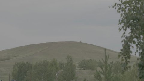 Silhouettes of a man and a woman standing on the hill and talking