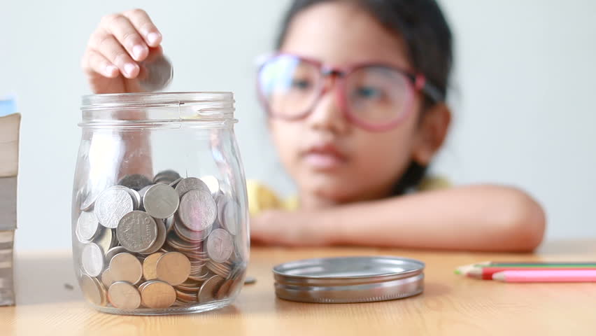 Asian little girl putting the coin into a  clear glass jar on table metaphor saving money concept with sound select focus on jar | Shutterstock HD Video #30196333
