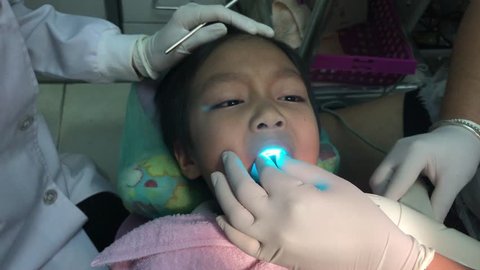 Dentists And Dental Assistant are filling a cavity and Pulling a teeth with cute asian boy