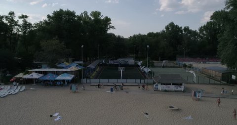 Ukraine. Kiev. August 18, 2017. Hydropark. Aerial. Beach. Bathe people. Trees. River Dnieper. Green water. The sun. Sky. Sunset. Sun beds. Swimming vessels. Volleyball. Basketball field. Beach Soccer.