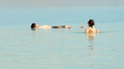 Dead Sea, Israel - May 22, 2017: People are bathing and swimming in the Dead Sea. The salinity of the dead sea water makes people floating in water. Dead sea is located between Jordan and Israel.