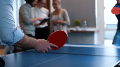 workers taking a break and playing ping pong in a creative start up work environment -