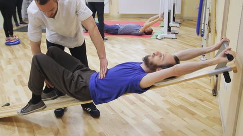 Physiotherapist helping young man, doing exercises at the rehabilitation center. Healthy gymnastics. Active people.
