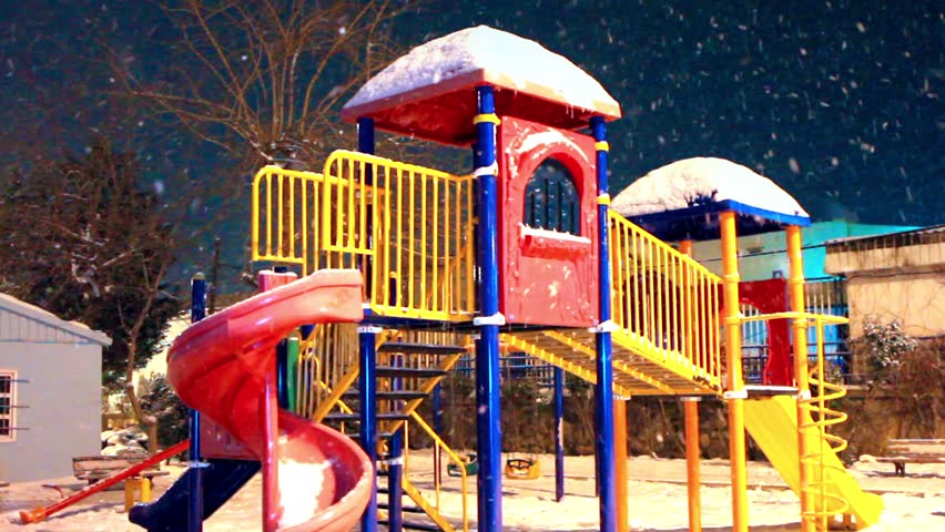 Colorful playground in snowfall night. Seamless loop
