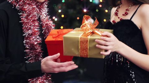 young man and woman exchanging of gifts at party