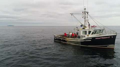 A cool aerial shot of professional fishermen catching lobster on their commercial fishing boat off the coast of Nova Scotia Canada