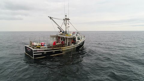 A cool aerial shot of professional fishermen catching lobster on their commercial fishing boat off the coast of Nova Scotia Canada