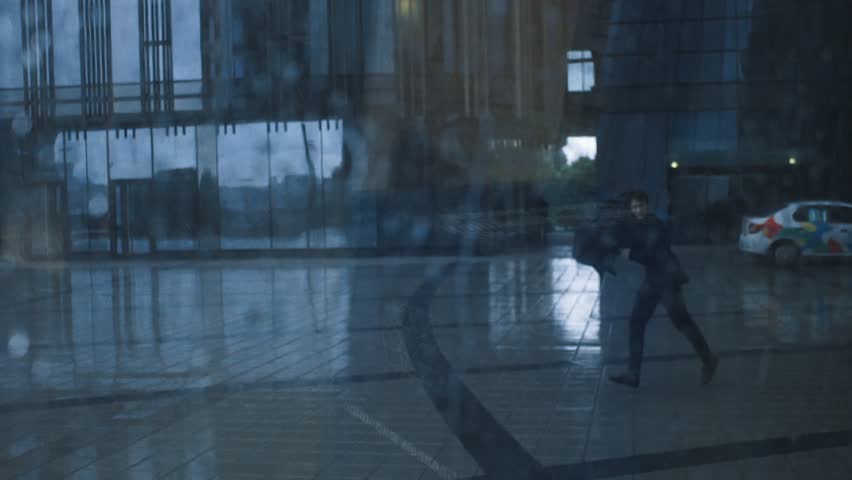 Young businessman in suit with umbrella under rain. Business centre building at the background. View through window with drops of water. Young man is running with an umbrella in the rain Royalty-Free Stock Footage #30220546