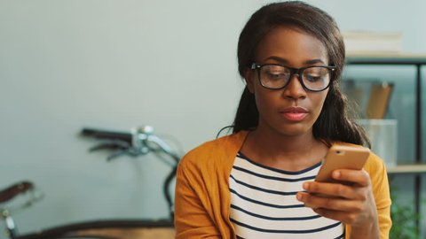 Portrait of young business african american woman using smart phone for chatting while drinking coffee during lunch time in the office.