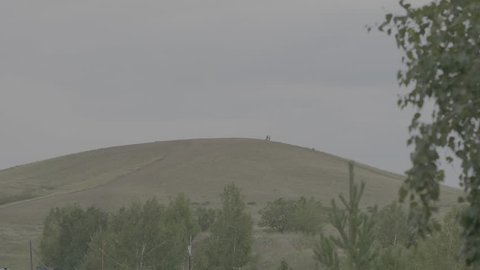Silhouettes of a man and a woman standing on the hill and talking