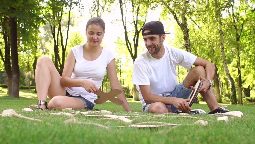 Young boy and girl playing TIC TAC toe large wooden figures in a Park on the grass. Large outdoor games. Slow motion.