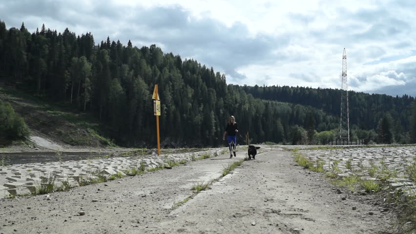 young beautiful girl in sports clothes running with her pet dog labrador