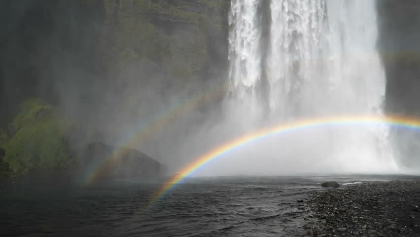 Skogafoss waterfall Iceland, slow motion mist rainbow over stream