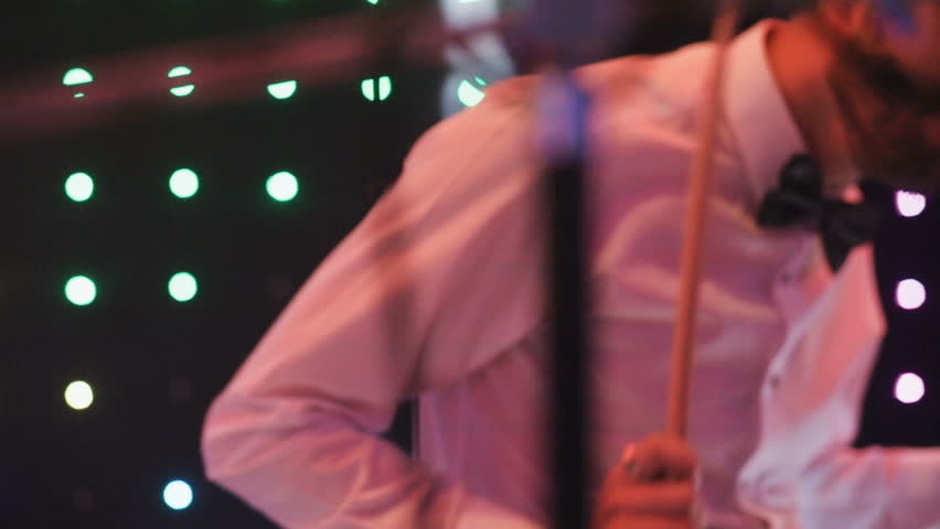 Close-up of a young man playing drums on stage. Waves her head. Satisfaction. On the concert