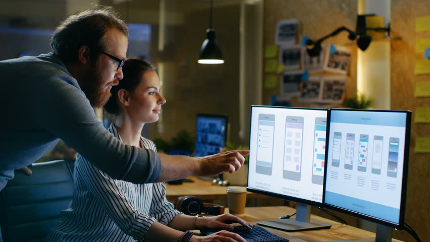 Female UX Architect Has Discussion with Male Design Engineer, They Work on Mobile Application Late at Night, She Drinks Coffee. In the Background Wall with Project Sticky Notes. Shot on RED EPIC-W 8K  | Shutterstock HD Video #30236200