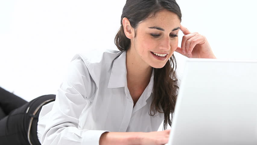 Video of a woman lying on belly while using a laptop