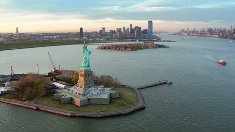  Aerial view of the Statue of Liberty at sunset. Manhattan and New Jersey skyline. New York City, United States. Shot from helicopter.