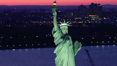 Aerial view of the Statue of Liberty at dusk. Manhattan and New Jersey skyline. New York City, United States. Close-up. Shot from helicopter.