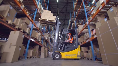 forklift operator puts boxes with goods on the metal racks