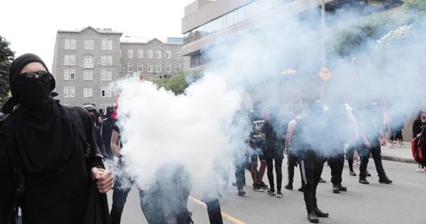 Quebec, Canada - August 2017 - A protester throws a smoke bomb during an anti-racism protest.