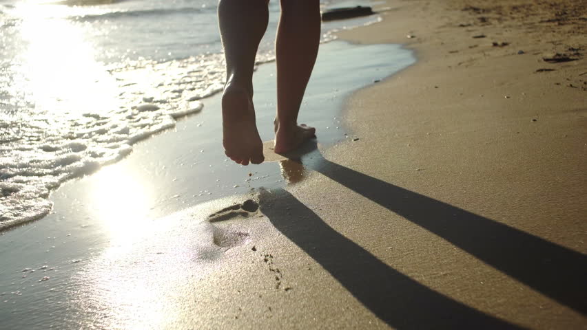 A young woman leaves footprints in the sand during the sunset. | Shutterstock HD Video #30251455