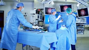 European male Caucasian surgical team in scrubs training performing Laparoscopy surgery on the patient in operating theatre using video camera technology RED DRAGON