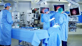 Caucasian male surgical team in scrubs in the operating theater of medical hospital using an Endoscopy to specialise in Laparoscopic surgery via video camera technology RED DRAGON