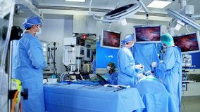 Laparoscopic surgical operation transmitted on hospital monitors performed by male Caucasians and African American training as surgeons wearing surgical gloves and scrubs RED DRAGON