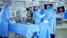 Laparoscopy surgical operation transmitted on hospital monitors performed by male Caucasians training as surgeons wearing surgical gloves and scrubs RED DRAGON