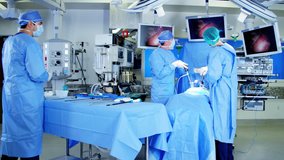 European male Caucasian surgical team in scrubs performing Laparoscopy surgery on the patient in operating theatre using video camera playback technology RED DRAGON